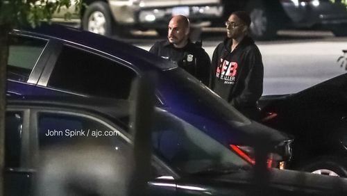 Morehouse College student Deaven Rector, 19, stands with an Atlanta police officer as authorities tow away his Toyota Corolla for processing. Rector’s car was stolen from him in southwest Atlanta Tuesday morning and later recovered.