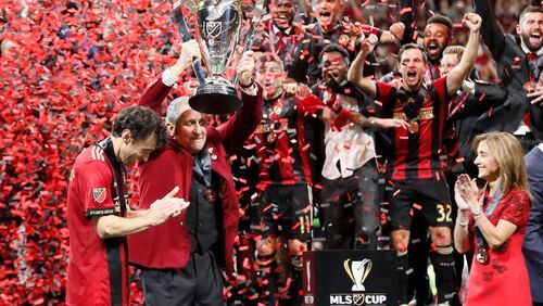 Arthur Blank raises the MLS Cup with Atlanta United defender Michael Parkhurst (3) after the victory as his wife looks on.   The Atlanta United soccer team defeated the Portland Timbers for the MLS Cup, the championship game of the Major League Soccer League at Mercedes-Benz Stadium in Atlanta.  BOB ANDRES / BANDRES@AJC.COM