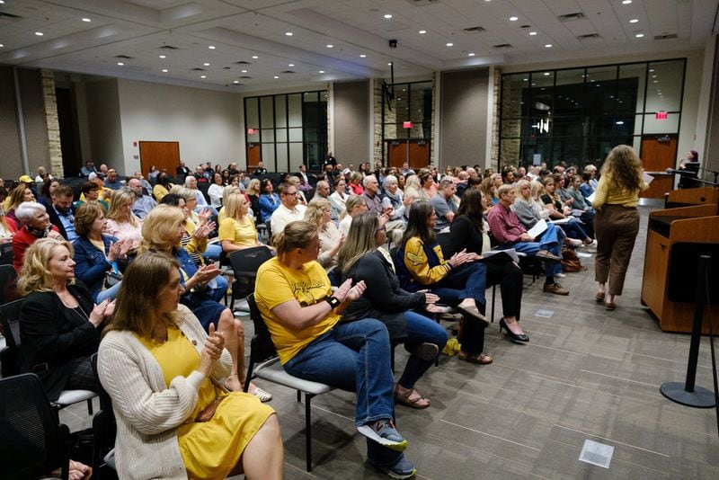 Audience members are seen clapping at a Cherokee County school board meeting in Canton on Thursday, April 21, 2022. Members of the public spoke both for and against removing books that some deem objectionable. People who objected to removing books from schools wore yellow as a sign of solidarity. (Arvin Temkar / arvin.temkar@ajc.com)