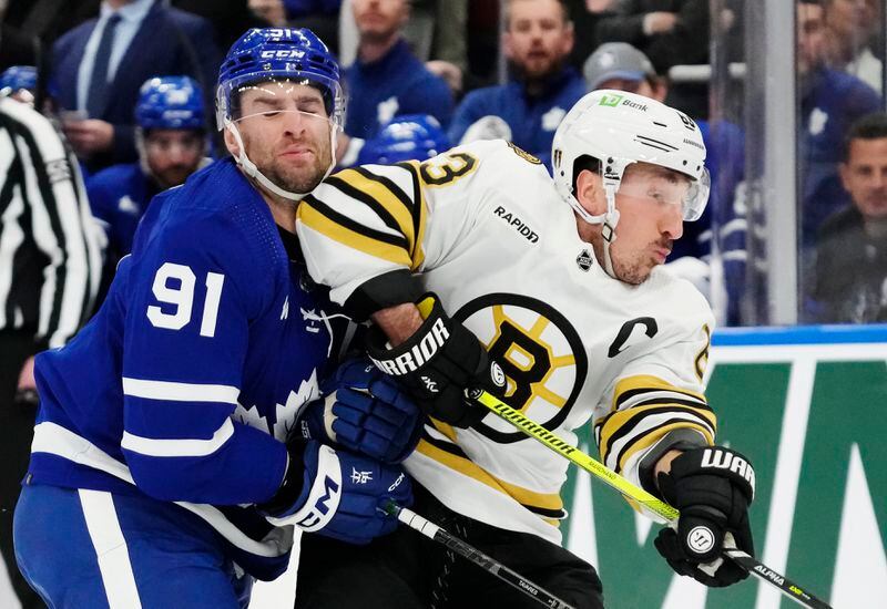 Toronto Maple Leafs' John Tavares (91) takes an elbow from Boston Bruins' Brad Marchand (63) during first-period action in Game 4 of an NHL hockey Stanley Cup first-round playoff series in Toronto, Saturday, April 27, 2024. (Frank Gunn/The Canadian Press via AP)