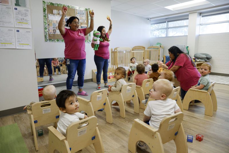 Caregivers Claudel Lepe, left, and Shyela Gonzaga, center, lead a song for a combined class of young infants and older infants at Little Mustangs Child Learning Academy, Wednesday, Feb. 21, 2024, in Richardson, Texas. (Elías Valverde II/The Dallas Morning News via AP)