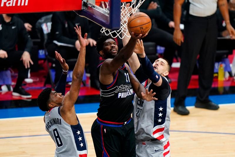 Philadelphia 76ers' Joel Embiid, center, goes up for a shot between Washington Wizards' Rui Hachimura, left, and Daniel Gafford during the first half of Game 1 of a first-round NBA basketball playoff series, Sunday, May 23, 2021, in Philadelphia. (AP Photo/Matt Slocum)