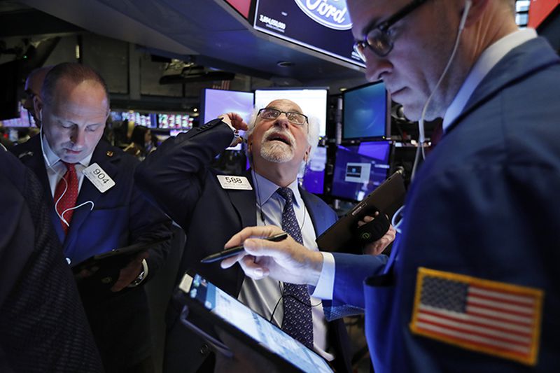 Traders Michael Urkonis, left, and Peter Tuchman, center, work on the floor of the New York Stock Exchange Monday.
