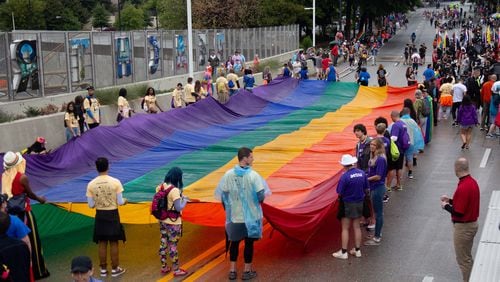People gather around a giant rainbow flag at the start of the 49th Annual Pride Festival and Parade in Atlanta Sunday, Oct 13, 2019.  STEVE SCHAEFER / SPECIAL TO THE AJC