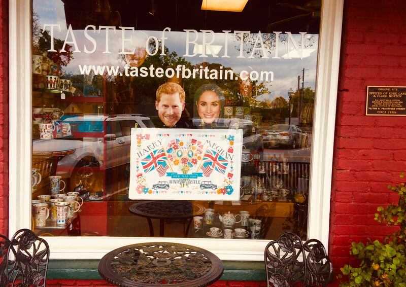 Harry and Meghan masks above a Royal Wedding tea towel peer out at passersby fromthe window of Taste of Britain in Historic Norcross. Jill Vejnoska/AJC