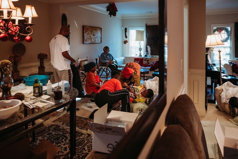 Dr. Rimani Kelsey-Rogers (center in yellow) gives birth to her daughter Sadia in her Atlanta home on Dec. 18, 2020. She's being tended by two midwives, a doula and her husband, Greg. (Chanda Williams / thebirthstorycollective.com)