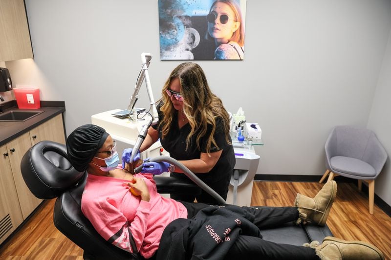 Tashayla Solomon gets a tattoo removed by laser specialist Shawn Brown at Removery in Sandy Springs. The tattoo was in sloppy script. She is having it removed. She plans to have the tattoo redone better later. (Arvin Temkar / arvin.temkar@ajc.com)
