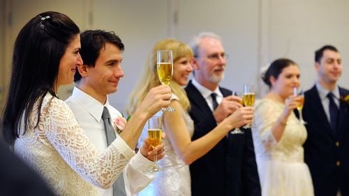 Newlyweds Katharine and Victor Serrano, left, join other couples for a champagne toast after exchanging vows during a mass wedding at Pinckneyville Park Community Recreation Center in Norcross in this 2014 file photo.