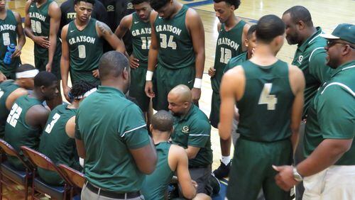 Grayson coach Geoffrey Pierce (kneeling) directs Rams players during a timeout of their AAAAAAA quarterfinals game against Pebblebrook in Mableton on Feb. 28, 2018.