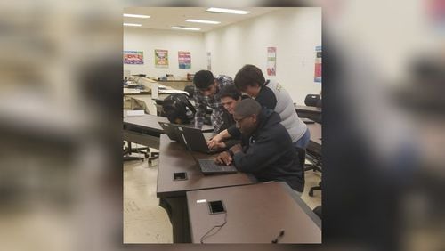 Henry County students in the system's cybersecurity program huddling around their computers during class.