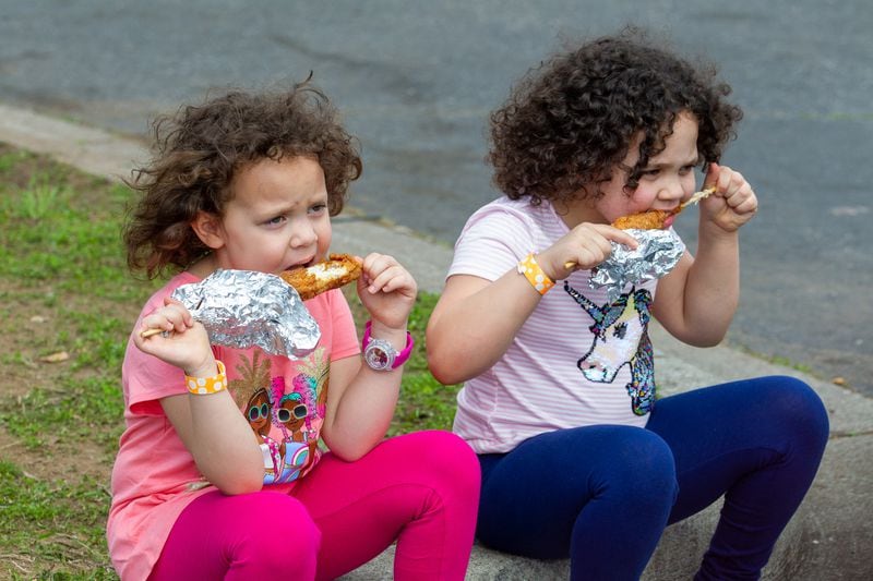 Jaylah Adams (left) and her sister Maya eat chicken on a stick while at Atlanta Fair on Sunday, March 6, 2022. (Photo by Steve Schaefer for The Atlanta Journal-Constitution)