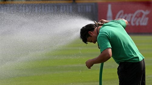 With temperatures expected to top another record today John Frazier, 34, a member of the Atlanta Braves ground crew, turns the hose on himself to cool down while preparing the field for the game against the Washington Nationals at Turner Field on Sunday, July 1, 2012.