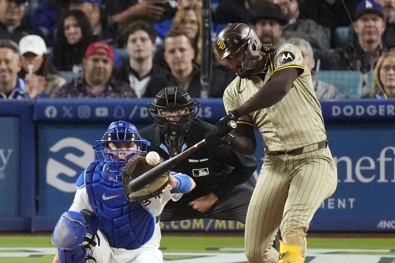 San Diego Padres' Fernando Tatis Jr., right, hits a two-run home run as Los Angeles Dodgers catcher Will Smith, left, and home plate Ryan Additon watch during the seventh inning of a baseball game April 12, 2024, in Los Angeles. Tatis Jr. plans to unveil 50 pairs of custom cleats this season.(AP Photo/Mark J. Terrill, File)