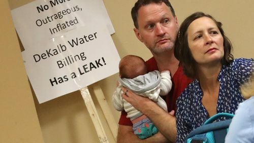 Matt and Star McKenizie, with newborn son Everett, were among DeKalb residents demanding answers about excessively high water bills during a town hall meeting at the Maloof Auditorium in Decatur on Nov. 10.  Curtis Compton/ccompton@ajc.com