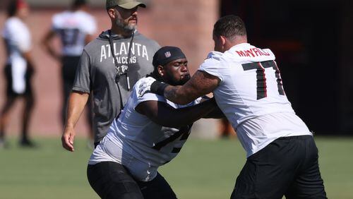 Falcons guard Justin Shaffer (75) does a drill with guard Jalen Mayfield (77) during training camp at the Falcons Practice Facility, Friday, July 29, 2022, in Flowery Branch, Ga. Also pictured is offensive line coach Dwayne Ledford. (Jason Getz / Jason.Getz@ajc.com)