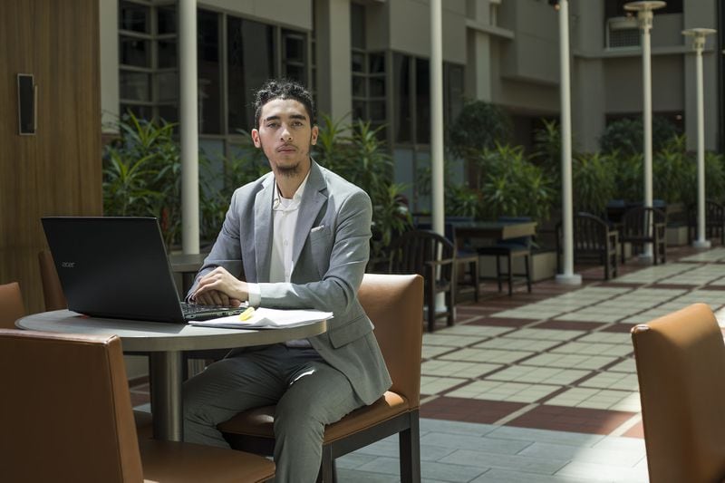 Morehouse College Business Finance freshman Joseph Ramirez sits in the closed bar at the Embassy Suites Hotel in downtown Atlanta, Thursday, April 16, 2020. Ramirez, whose family is in Los Angeles, completes his classes online and tries to get as much sunlight as he can while navigating life in a hotel. (ALYSSA POINTER / ALYSSA.POINTER@AJC.COM)