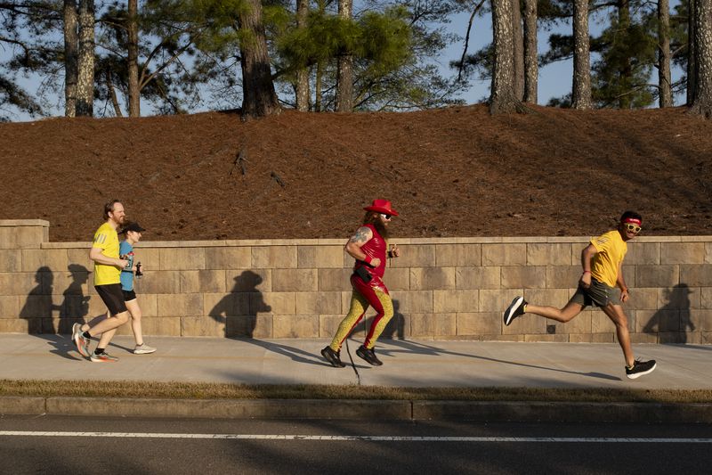 Runners with Big Peach Running Co. Alpharetta’s Wednesday night running group heads towards the Big Creek Greenway during an ’80’s themed run March 20, 2024.  (Ben Gray / Ben@BenGray.com)