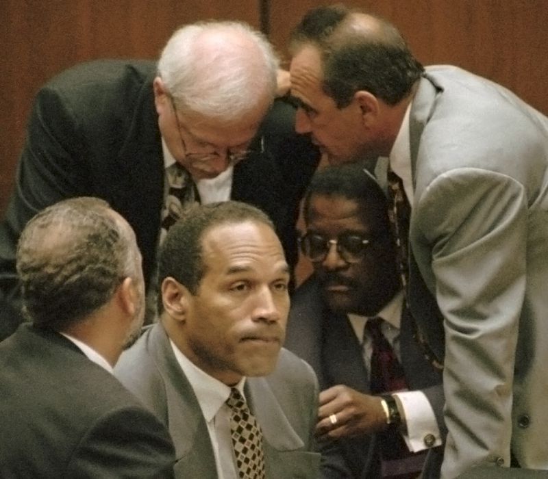 FILE - O.J. Simpson is surrounded by his defenseattorneys, clockwise from left, Ken Spaulding, back towards camera, Gerald Uelmen, Robert Shapiro and Johnnie Cochran Jr., as they discuss their plans for arguing the admissibility of the tapes of retired Los Angeles police detective Mark Fuhrman during his trial, Tuesday, Aug. 29, 1995 in Los Angeles. Simpson, the decorated football superstar and Hollywood actor who was acquitted of charges he killed his former wife and her friend but later found liable in a separate civil trial, has died. He was 76. (Myung J. Chun/Los Angeles Daily News via AP, Pool, File)