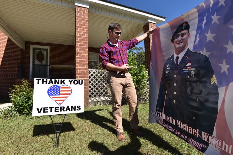 Will Wright holds a banner of Dustin Wright at his home in Lyons on Tuesday, October 24, 2017. HYOSUB SHIN / HSHIN@AJC.COM