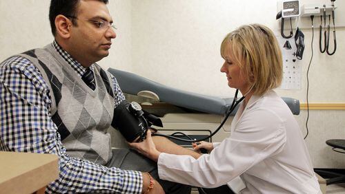 Nurse practitioner Holly McDonald checks the blood pressure of Sujal Patel of Decatur during a physical exam at the MinuteClinic inside the Virginia-Highland CVS.
