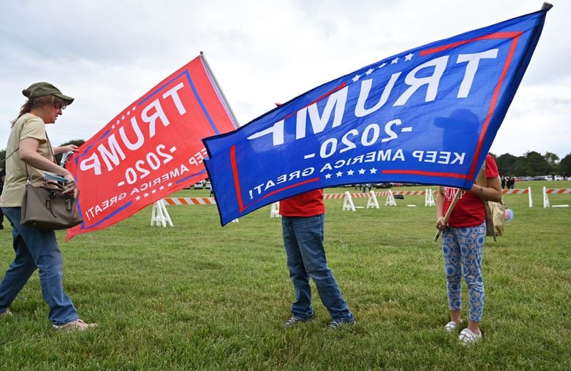 Dora Aguillon of Cumming and her two children, Nicolas, 10, and Rita (right), 9, display flags supporting President Donald Trump's reelection campaign. Aguillon, who said she is concerned about creeping socialism, is confident Trump will win in Atlanta's suburbs. (Hyosub Shin / Hyosub.Shin@ajc.com)