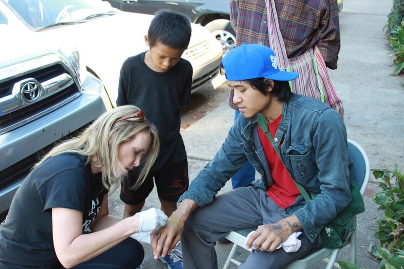 Kelli Czaykowsky tends a wound on the hand of a refugee boy. CONTRIBUTED BY ALLEN CLARK
