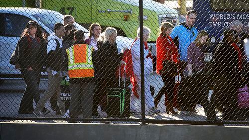 Passengers leave a fire station as they board a shuttle taking them off the tarmac at Hartsfield-Jackson Atlanta International Airport where two airplanes were being searched after authorities received what they described as credible bomb threats, Saturday, Jan. 24, 2015, in Atlanta. (AP Photo/David Goldman)