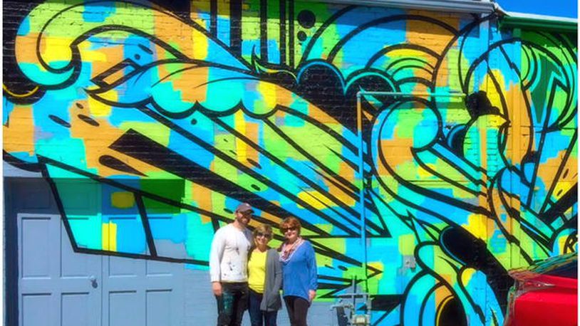 Artist Peter Ferrari completed his mural “Verb" last month on Norcross' Skin Alley. He is shown here with Norcross Public Arts Commission members Deb Harris and Cindy Flynn. (Credit: Norcross Public Arts Commission)