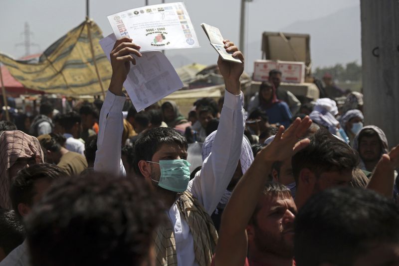 Hundreds of people gathered, some holding documents, near an evacuation control checkpoint on the perimeter of the Hamid Karzai International Airport, in Kabul, Afghanistan, on Aug. 26.  (AP Photo/Wali Sabawoon)