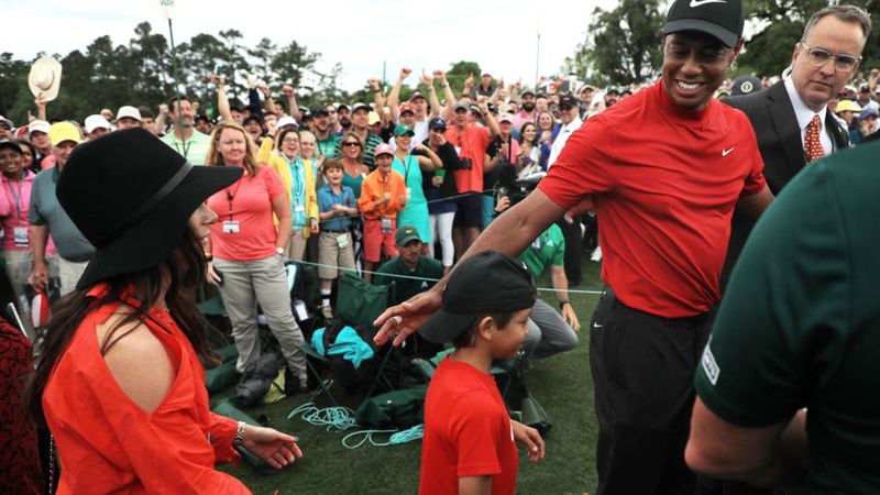 Tiger Woods (R) of the United States  celebrates with his girlfriend Erica Herman (L) and son Charlie Axel (C) as he comes off the 18th green in celebration of his win during the final round of the Masters at Augusta National Golf Club on April 14, 2019 in Augusta, Georgia.