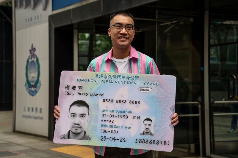 Activist Henry Tse, who won an appeal to change the gender on his ID card, poses with a mock ID card outside the immigration tower after receiving the new document in Hong Kong, Monday, April. 29, 2024. The Hong Kong transgender activist who fought a years-long legal battle to change the gender on his official identity card finally received the new document on Monday, vowing to continue working hard on the unfinished path of fighting for equality for his community. (AP Photo/Vernon Yuen)