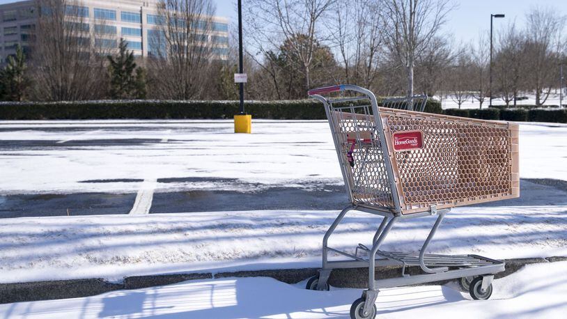 Some shopping gets put off because of the storm and just gets postponed until later. An abandoned shopping cart rests in the snow near shopping center in Alpharetta. ALYSSA POINTER/ALYSSA.POINTER@AJC.COM