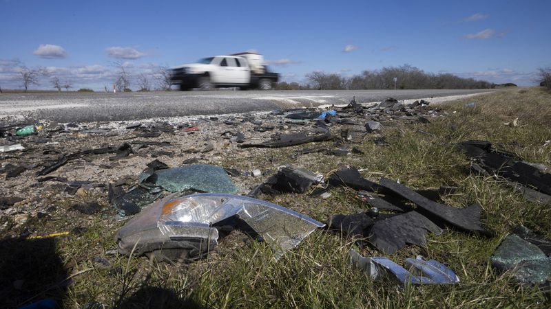 Drivers pass by debris where six people were killed in a crash on U.S. 67 in Texas.