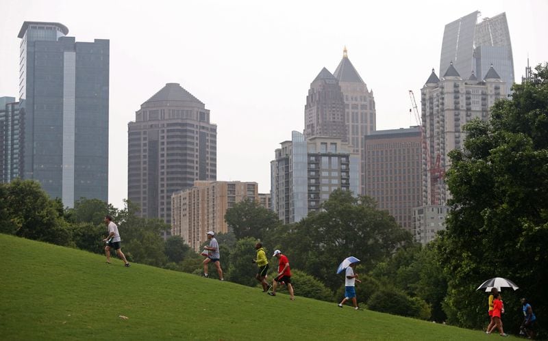 Runners and spectators walk on a hill at Piedmont Park with the Midtown skyline in the background during the 46th running of the Atlanta Journal-Constitution Peachtree Road Race Saturday morning in Atlanta, Ga., July 4, 2015. JASON GETZ / PHOTO