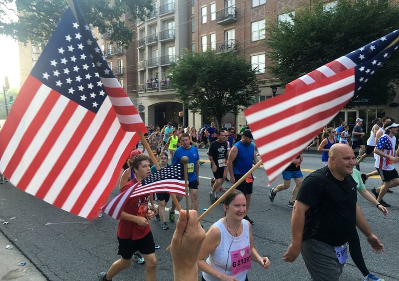 In this file photo, a fan waves flags and cheers runners on Cardiac Hill during the AJC Peachtree Road Race. Ben Gray / bgray@ajc.com