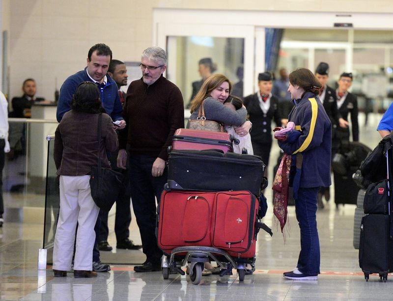 Mansour Kenereh (center in purple sweater) reunites with family members in the International arrivals lobby at Hartsfield Jackson International Airport Saturday January 25, 2017. The family of 3 were among several people detained at the Customs and Border Protection office following an executive order from President Trump limiting immigration. (Kent D. Johnson/AJC )