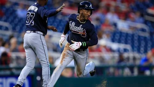 Atlanta Braves' Ozzie Albies, right, watches the ball as he runs to home plate to score during the first inning of a baseball game against the Washington Nationals in Washington, Tuesday, Sept. 12, 2017. (AP Photo/Manuel Balce Ceneta)