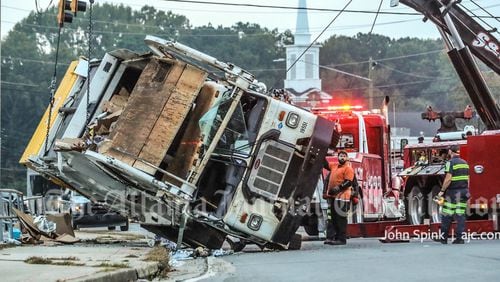 A crane was brought in to upright a garbage truck after it tipped on its side Friday morning on Lawrenceville Highway.