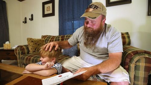U.S. Army veteran Bobby Fisk helps his 5-year-old son Oi with his math homework. Fisk, who suffered injuries from two IED explosions in Afghanistan, has had multiple problems getting health care at the VA. Curtis Compton/ccompton@ajc.com