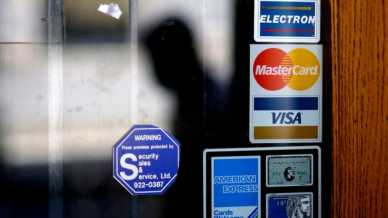 In this July 18, 2012, file photo, a pedestrian walks past credit card logos posted on a downtown storefront in Atlanta. On Monday, Sept. 11, 2017, Equifax said it has made changes to address customer complaints since it disclosed a week earlier that it exposed vital data on about 143 million Americans. Equifax has come under fire from members of Congress, state attorneys general, and people who are getting conflicting answers about whether their information was stolen. Equifax is trying again to clarify language about people's right to sue, and said Monday it has made changes to address customer complaints. (AP Photo/David Goldman, File)