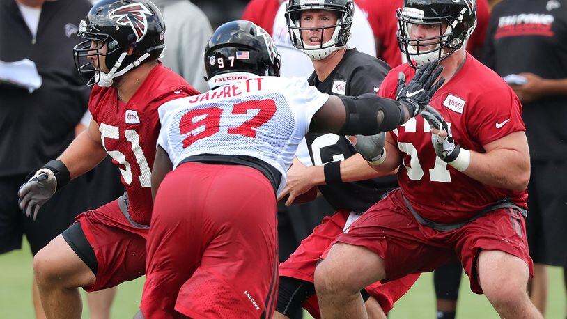 072816 FLOWERY BRANCH: Falcons Andy Levitre (right) and Alex Mack blocks for quarterback Matt Ryan while Grady Jarrett defends during the first day of training camp on Thursday, July 28, 2016, in Flowery Branch. Curtis Compton /ccompton@ajc.com