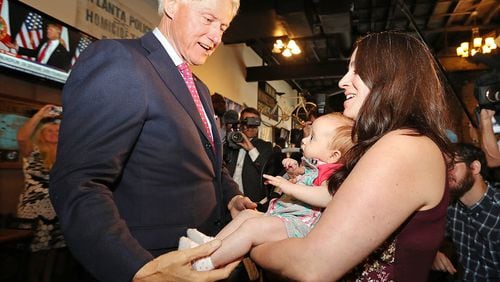 Former President Bill Clinton says hello to Megan Bartlett of Decatur and her 3-month-old daughter, Hannah Rice, as he works the crowd Wednesday during a campaign stop at Manuel’s Tavern. Curtis Compton /ccompton@ajc.com