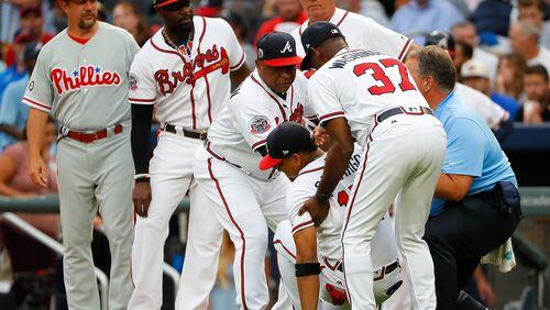 Bench coach Terry Pendleton #9, third base coach Ron Washington #37 and trainer Jim Lovell of the Atlanta Braves help up Johan Camargo #17 after he fell to the ground running onto the field in the first inning to face the Philadelphia Phillies at SunTrust Park on August 8, 2017 in Atlanta, Georgia. (Photo by Kevin C. Cox/Getty Images)
