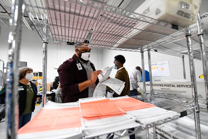 A worker looks through ballots while an observer looks on at left as votes for President are recounted at the Gwinnett County elections office on Friday, Nov.13, 2020 in Lawrenceville. (JOHN AMIS FOR THE ATLANTA JOURNAL-CONSTITUTION)
