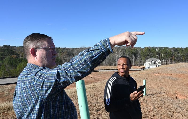 Mike Donithan (left) and Pernell Evans, homeowners at Parkview Estates in South Fulton, discuss an expanse of land sold in 2021 to ResiBuilt Homes, an Atlanta-based company with plans to finish the subdivision as rentals. (Hyosub Shin / Hyosub.Shin@ajc.com)