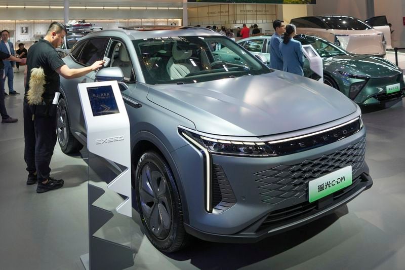 A worker cleans an Exeed C-DM car during the China Auto Show in Beijing, China, Friday, April 26, 2024. China's vision of the future of the automobile electrified and digitally connected is on display at the ongoing Beijing auto show. (AP Photo/Tatan Syuflana)