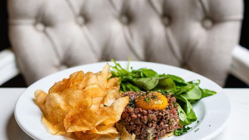 Steak tartare at the Brasserie is served with classic accouterments: dijon, shallots, cornichons, capers and an egg yolk. It’s served with house-made potato chips and a pile of bright salad greens. CONTRIBUTED BY HENRI HOLLIS