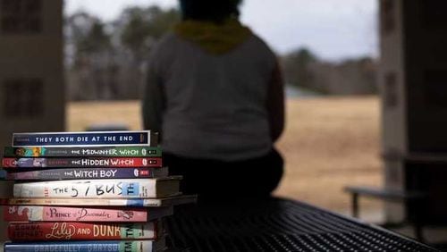 James Liming sits at a Forsyth County park with some books that were meaningful to him after he came out as transgender in the eighth grade. Liming, who graduated from high school last weekend, has been concerned that books are being banned from some schools based on race, gender or sexual orientation. Nov. 7, 2021. Ben Gray for The Atlanta Journal-Constitution.