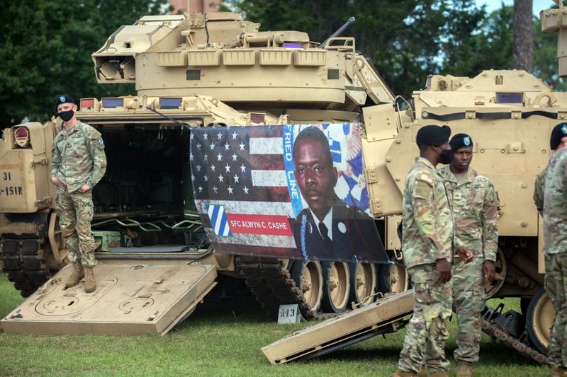 FORT STEWART, GA - MAY 20, 2021: A banner with a photograph of Sgt. 1st Class Alwyn Cashe hangs between two Bradley Fighting Vehicles during a ceremony to rename a memorial garden here in honor of him. (AJC Photo/Stephen B. Morton)