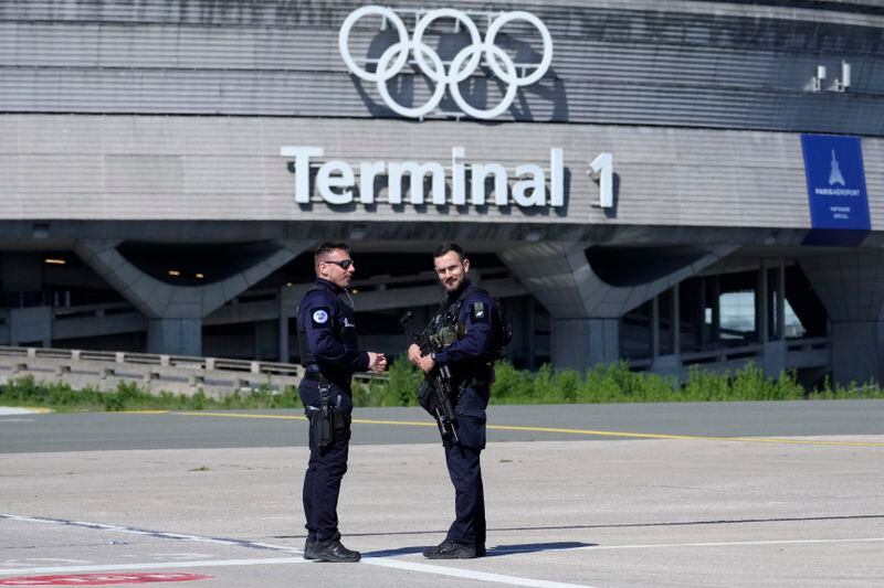 Gendarmes stand in from of the Charles de Gaulle airport, terminal 1, where the olympic rings were installed, is seen in Roissy-en-France, north of Paris, Tuesday, April 23, 2024 in Paris. (AP Photo/Thibault Camus)